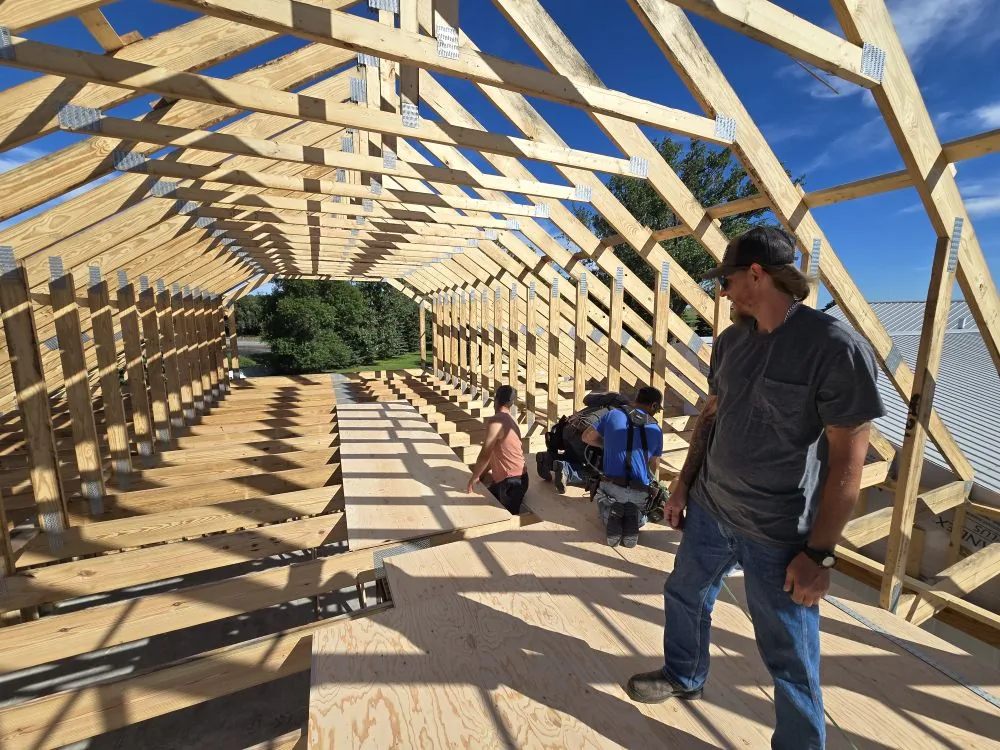 The Ranch Remodel — length view down the inside of the new trusses, bonus room deck below, crew setting the next bay.
