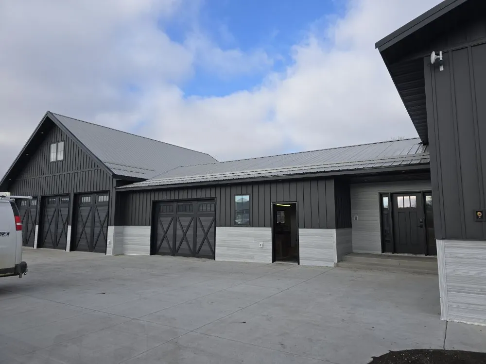 Modern farmhouse exterior with charcoal board-and-batten and three-bay barn-style garage — the Ranch Remodel.